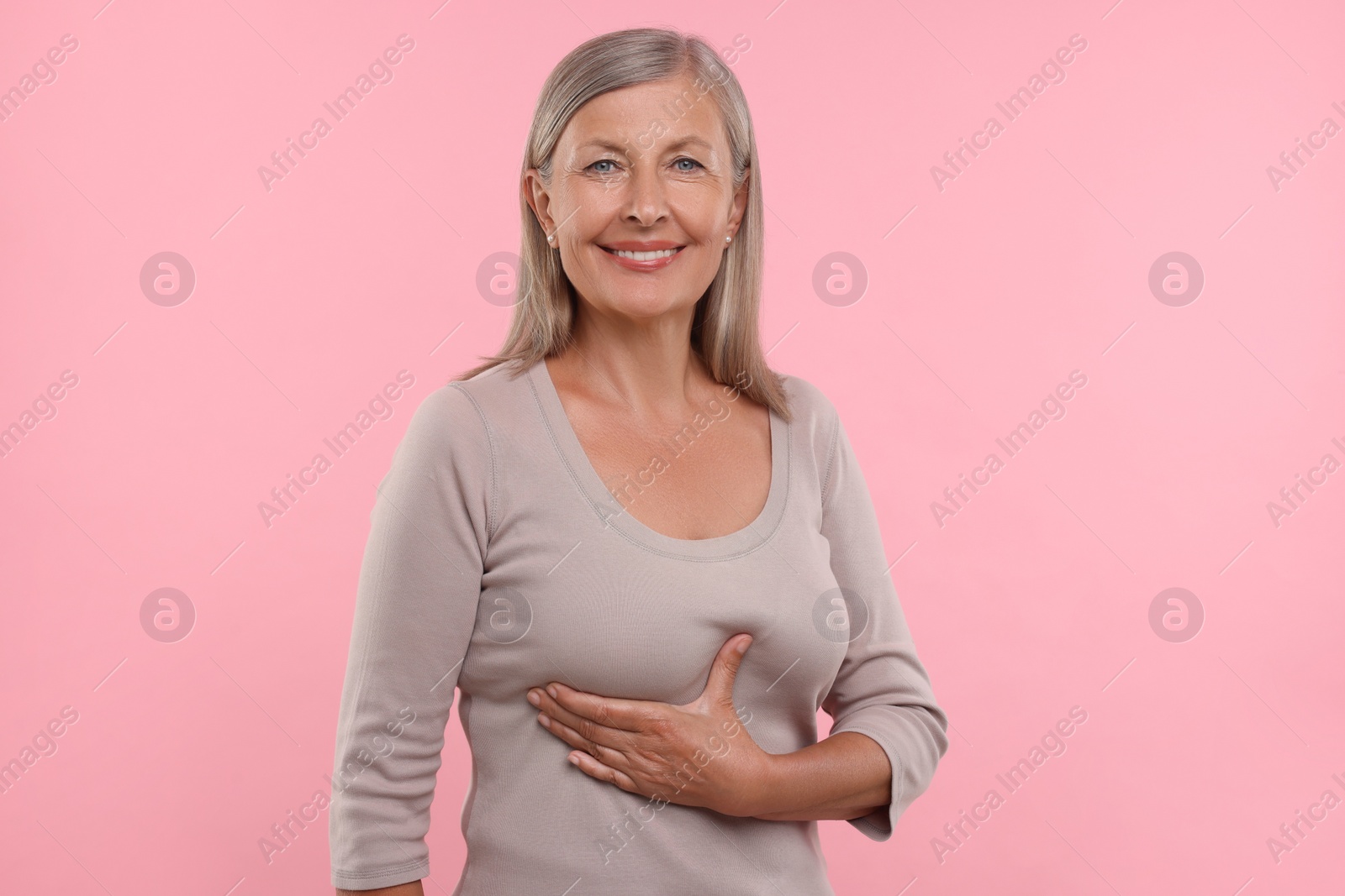 Photo of Beautiful senior woman doing breast self-examination on pink background