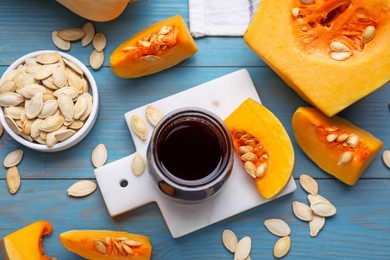 Photo of Flat lay composition with fresh pumpkin seed oil in glass jar on blue wooden table