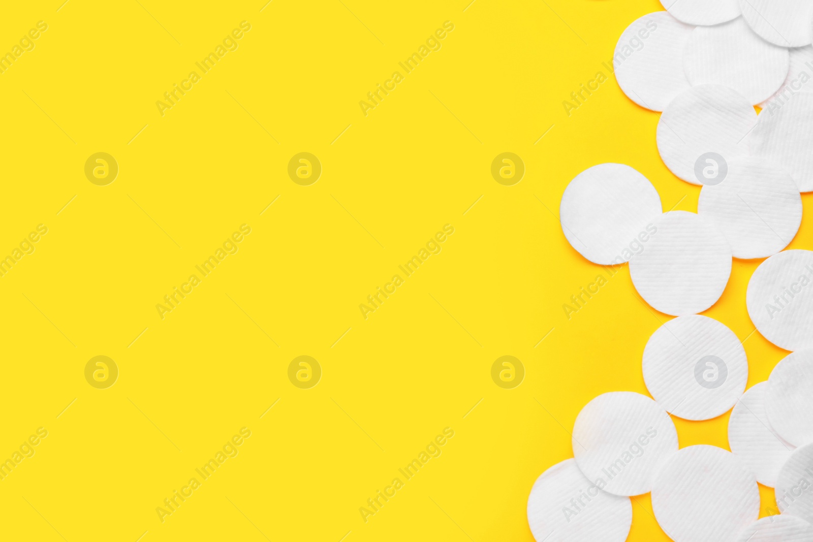 Photo of Soft clean cotton pads on yellow background, flat lay. Space for text