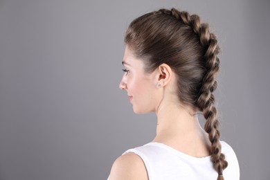 Woman with braided hair on grey background. Space for text