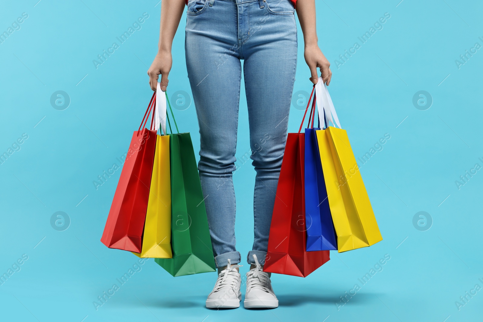 Photo of Woman with shopping bags on light blue background, closeup