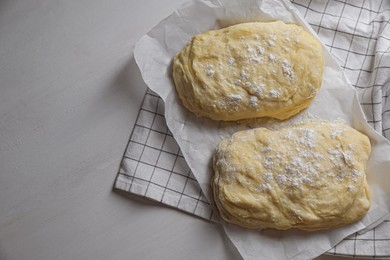 Raw dough and flour on white wooden table, top view with space for text. Cooking ciabatta