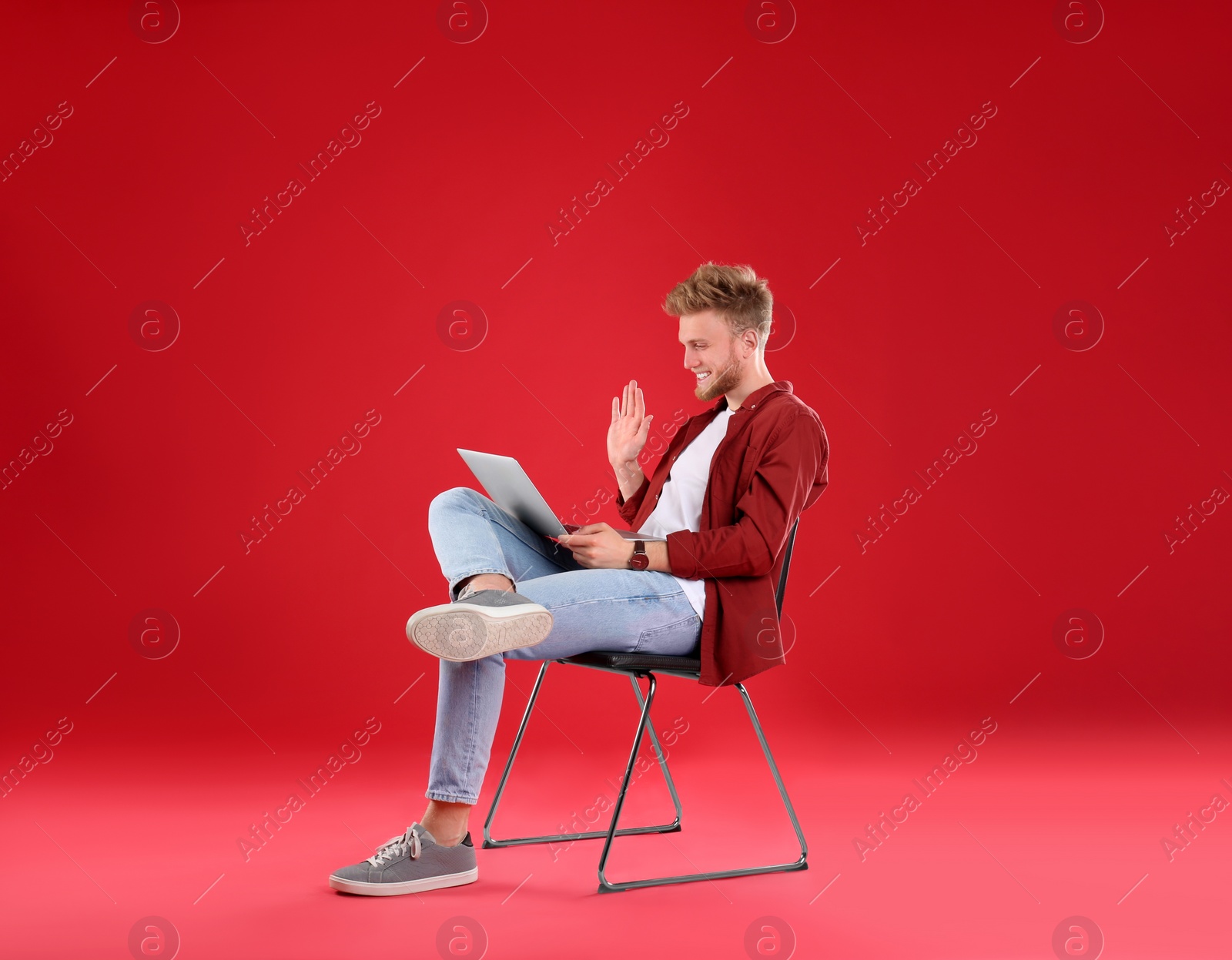 Photo of Happy man with laptop on red background