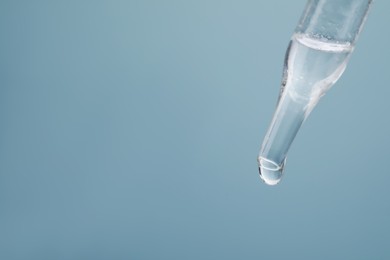 Photo of Dripping serum from pipette on grey background, closeup. Space for text