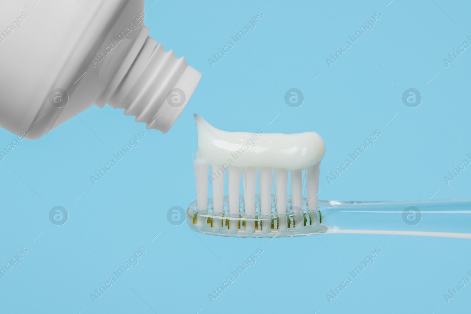 Photo of Electric toothbrush with paste on light blue background, closeup