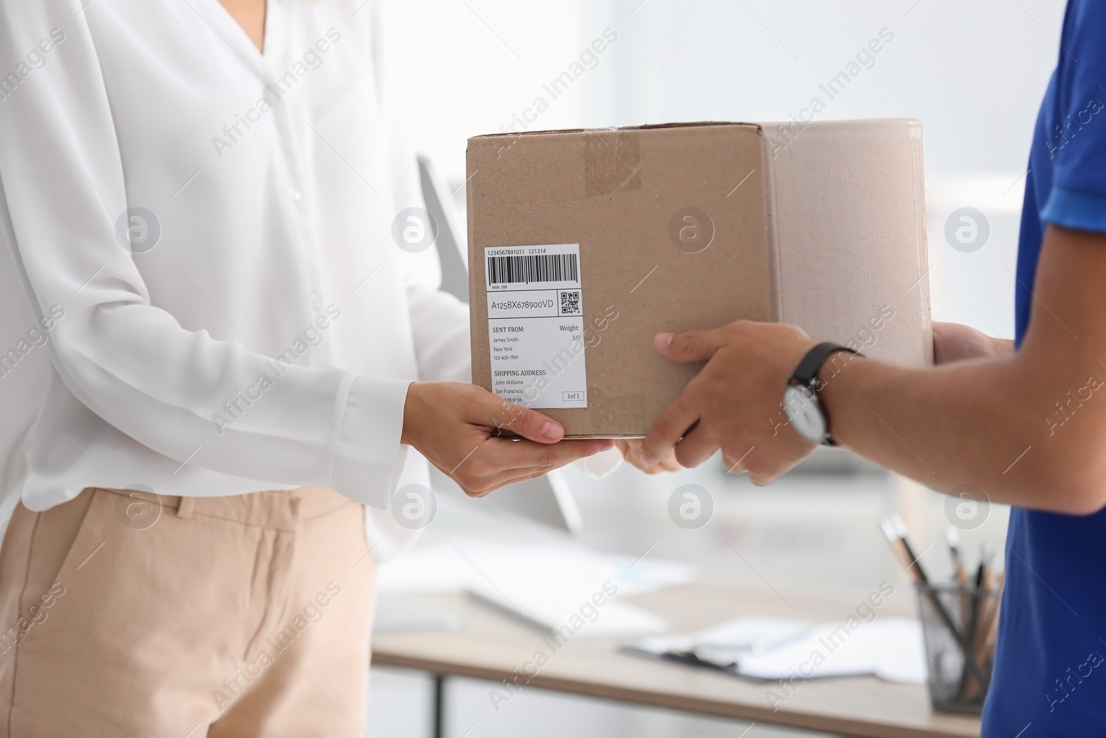 Photo of Young woman receiving parcel from courier in office