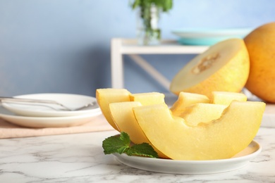 Plate with fresh delicious melon slices on table