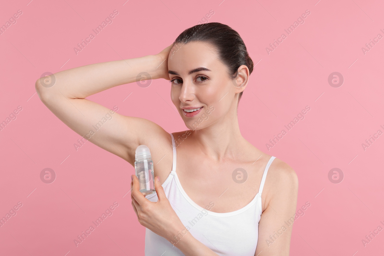 Photo of Beautiful woman applying deodorant on pink background