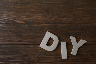 Photo of Abbreviation DIY made of letters on wooden table, flat lay. Space for text