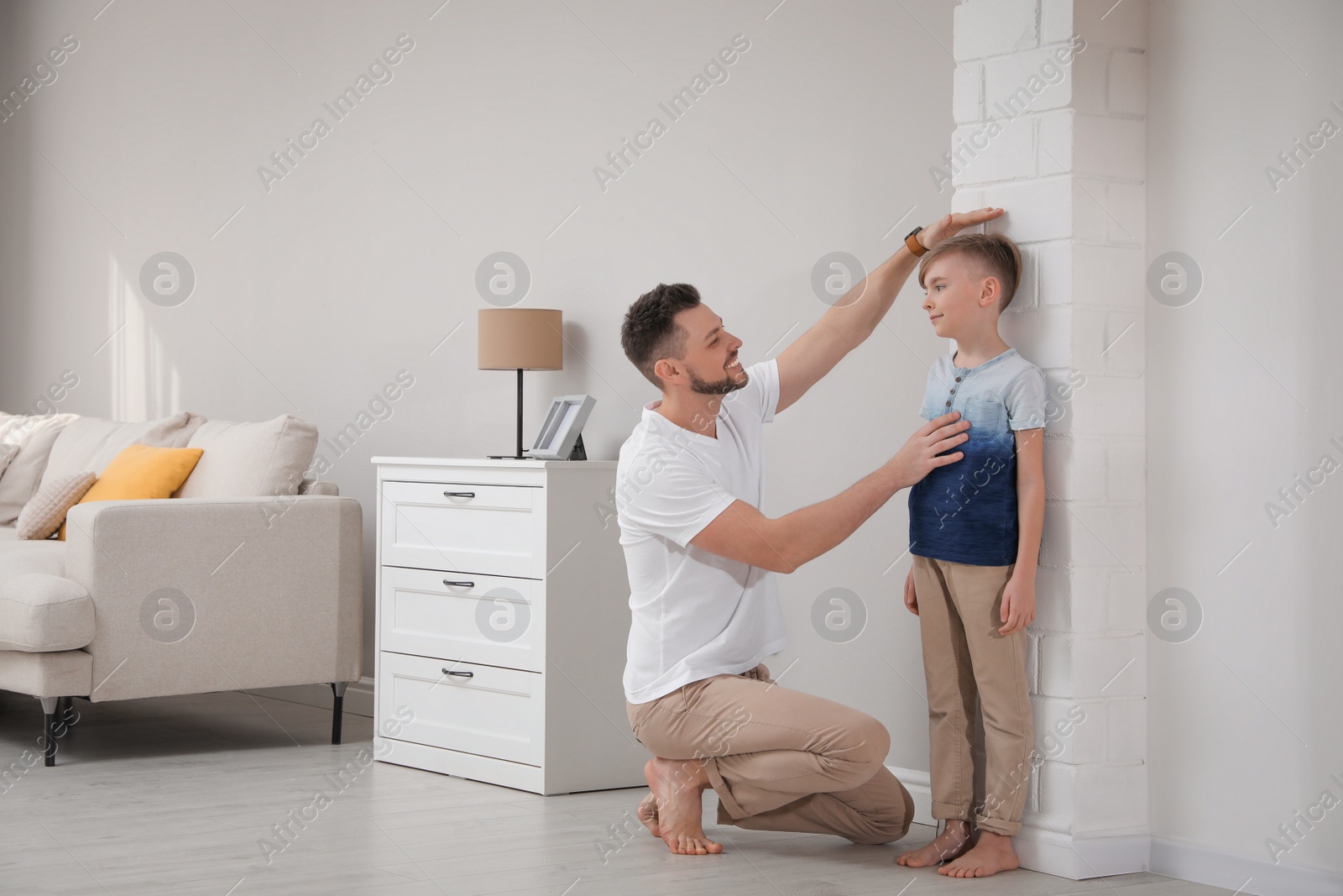 Photo of Father measuring height of his son near wall at home