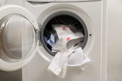 Photo of Men's shirt with lipstick kiss marks among other clothes in washing machine, closeup