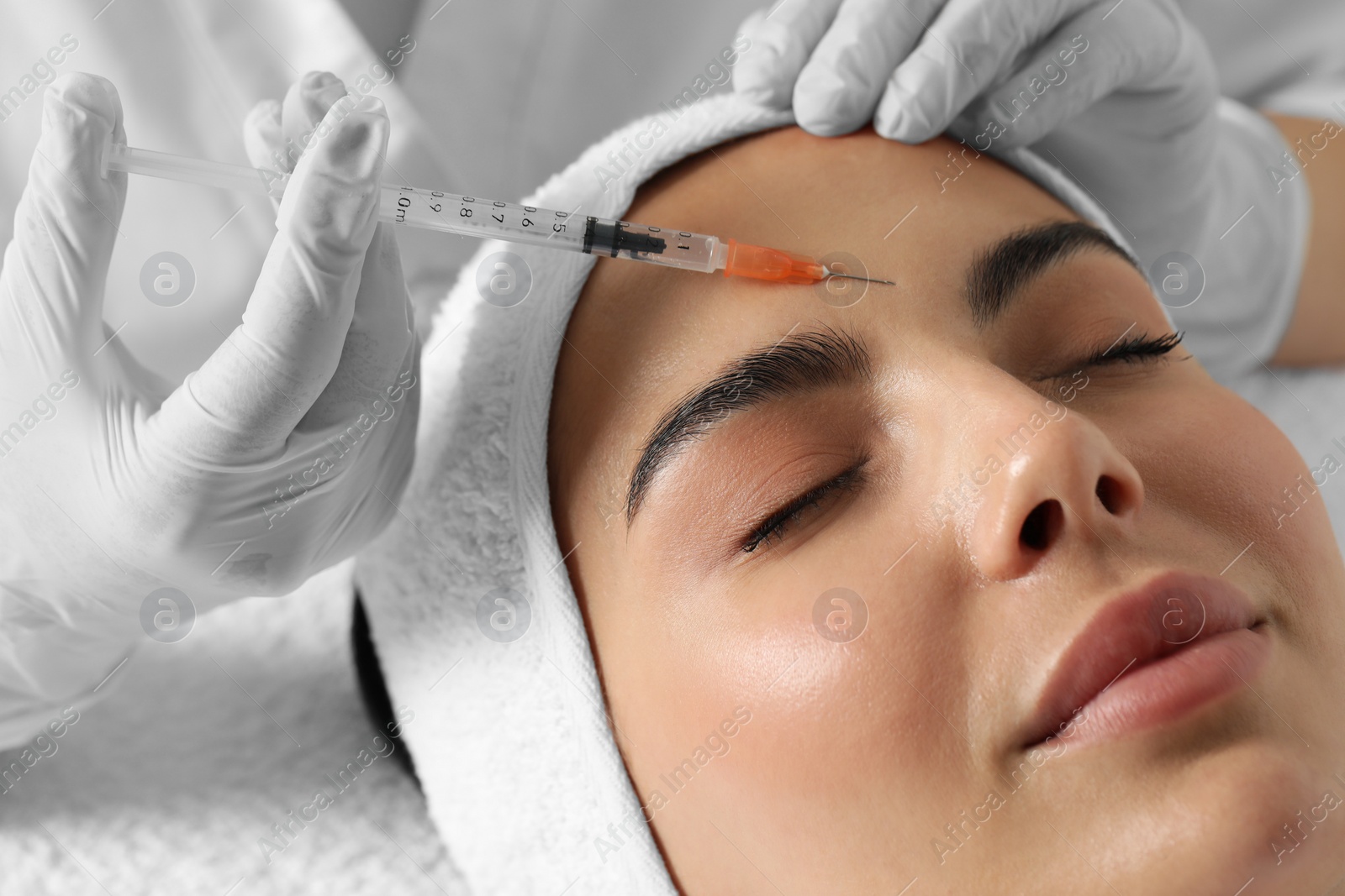 Photo of Doctor giving facial injection to young woman in clinic, closeup. Cosmetic surgery