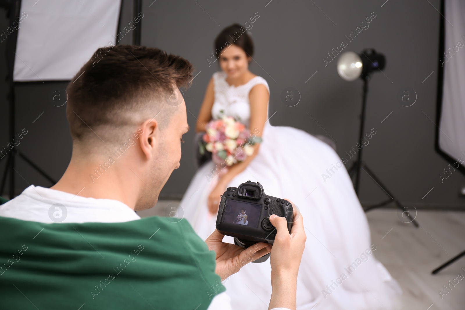 Photo of Professional photographer with camera and beautiful bride in studio