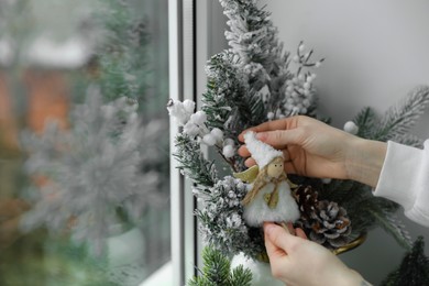 Photo of Woman decorating Christmas tree covered with artificial snow near window indoors, closeup. Space for text