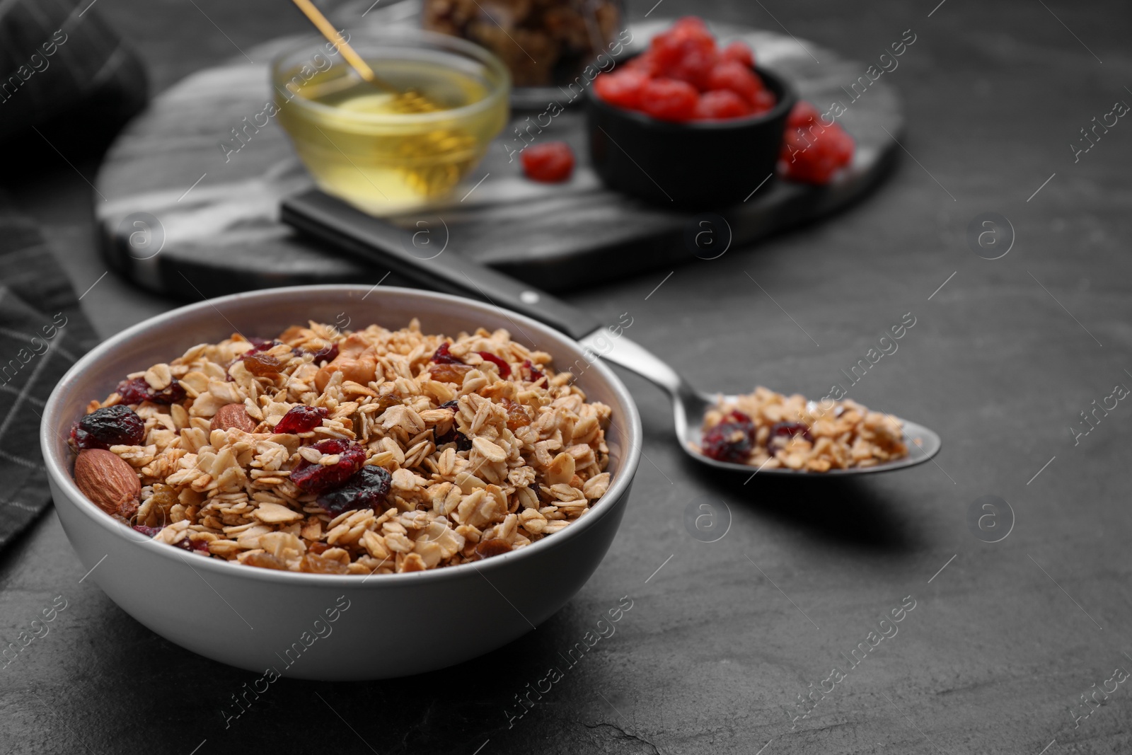 Photo of Tasty granola served with nuts and dry fruits on black table. Space for text