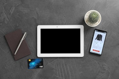 Photo of Online store. Tablet, smartphone, credit card, stationery and cactus on grey table, flat lay
