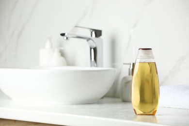 Bottle of shampoo near sink on bathroom counter, space for text