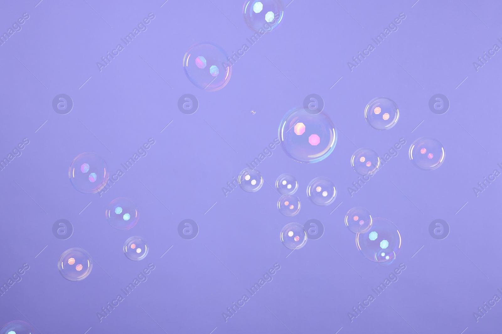 Photo of Many beautiful soap bubbles on violet background