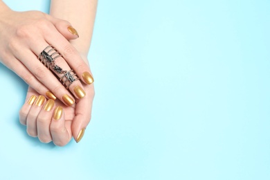 Photo of Woman showing manicured hands with golden nail polish on color background, top view. Space for text
