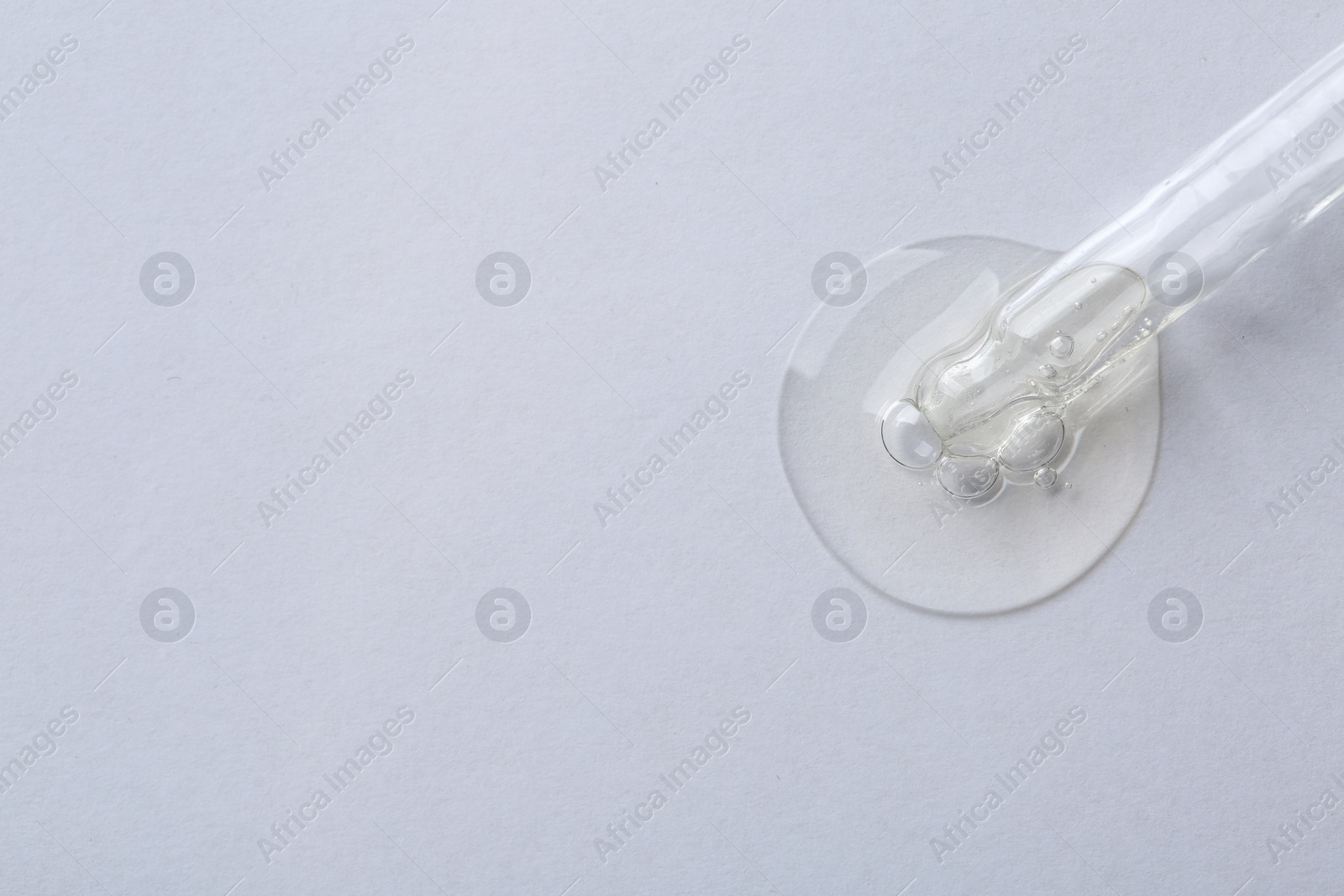 Photo of Pipette with cosmetic serum on white background, top view