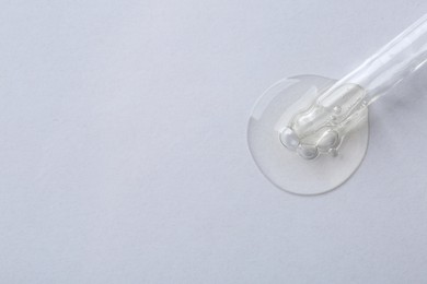 Pipette with cosmetic serum on white background, top view