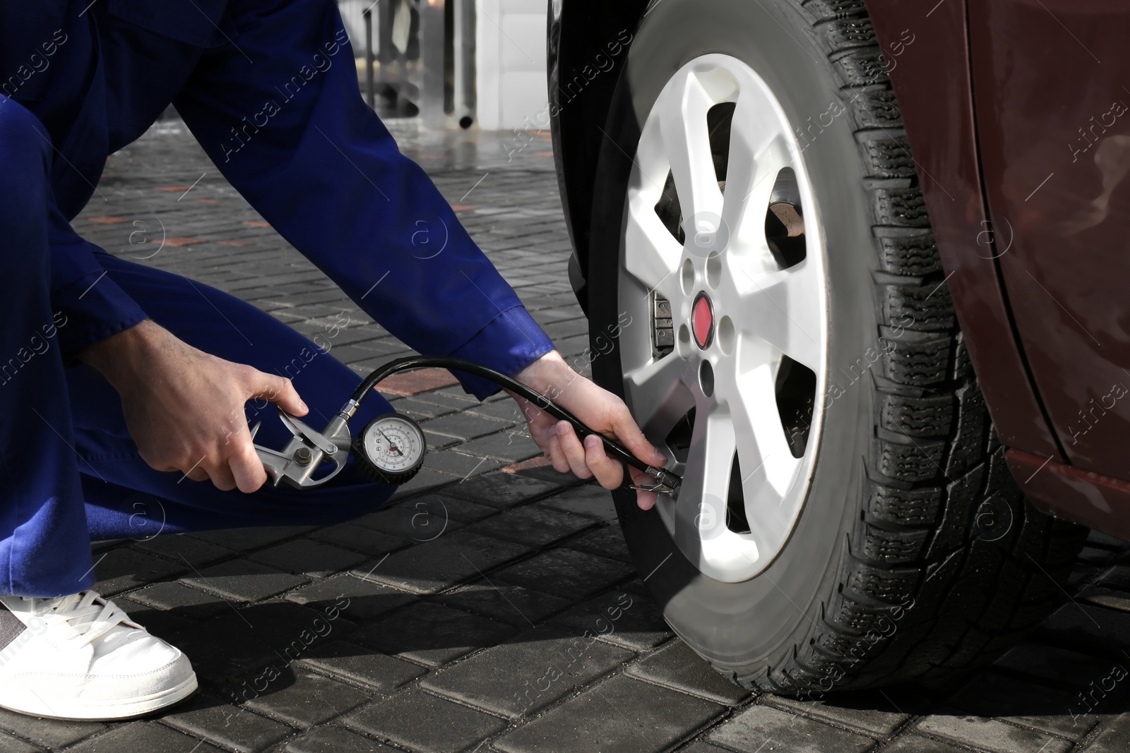 Photo of Mechanic checking tire air pressure at car service, closeup