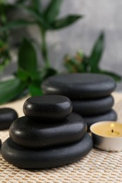 Photo of Stacked spa stones, bamboo and candle on wicker mat