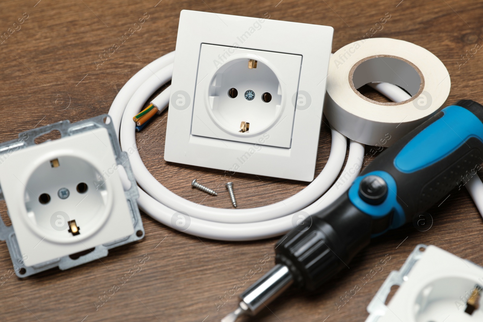 Photo of Power sockets, screwdriver, cable and insulating tape on wooden table