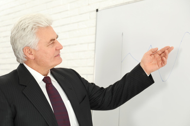 Photo of Senior business trainer near whiteboard in office