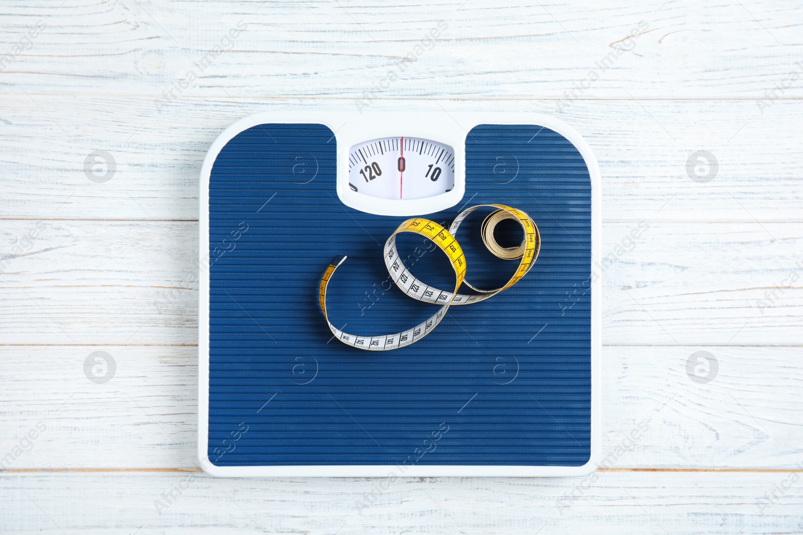 Photo of Scales and measuring tape on wooden background, top view. Weight loss