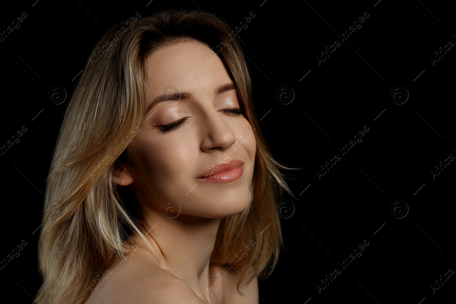 Photo of Portrait of happy young woman with beautiful blonde hair on black background, closeup. Space for text