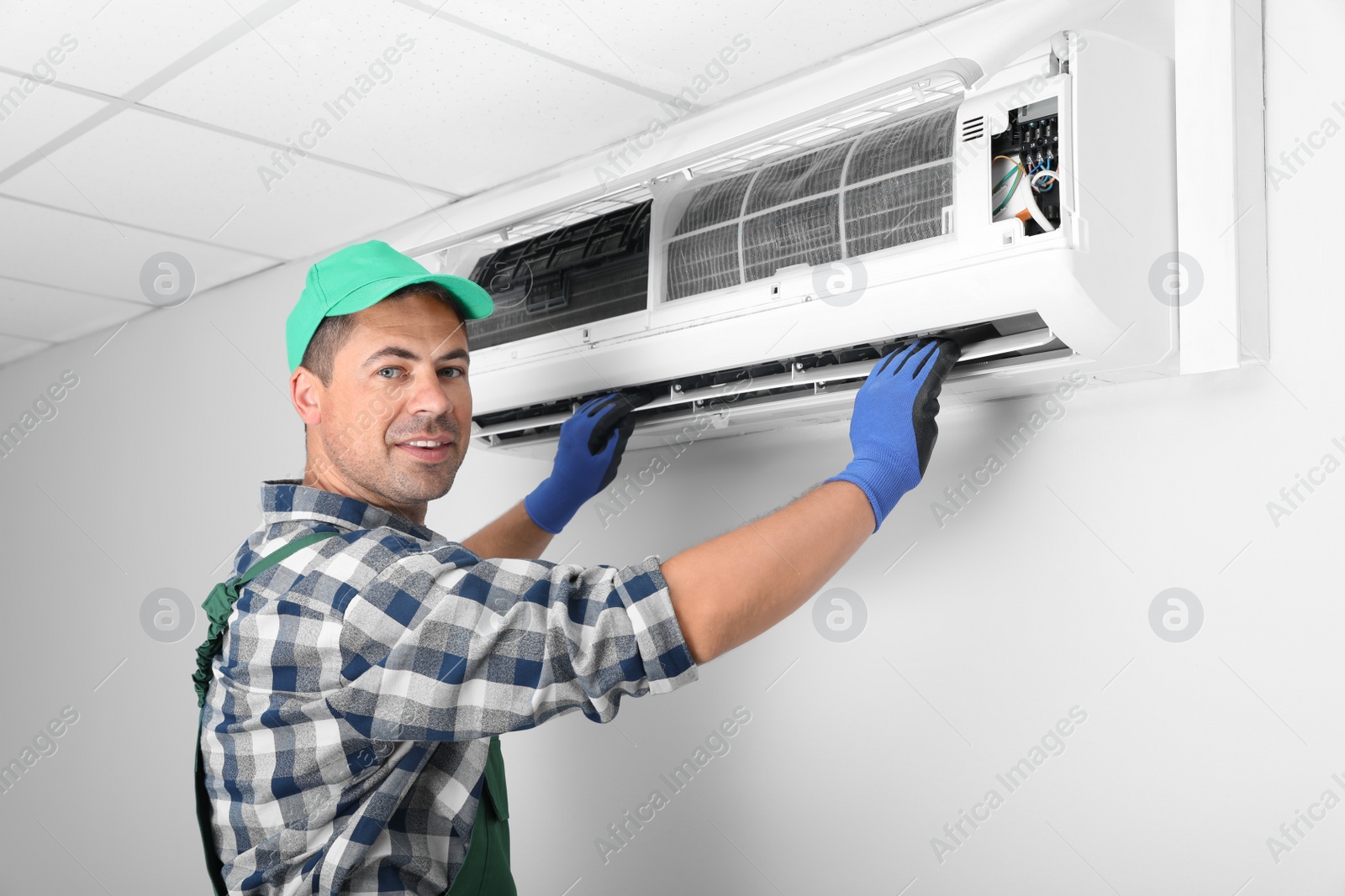 Photo of Male technician installing air conditioner indoors