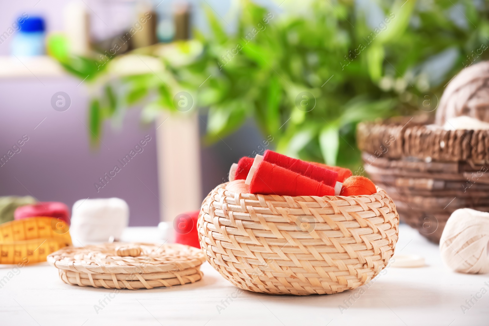 Photo of Wicker basket with color sewing threads on table