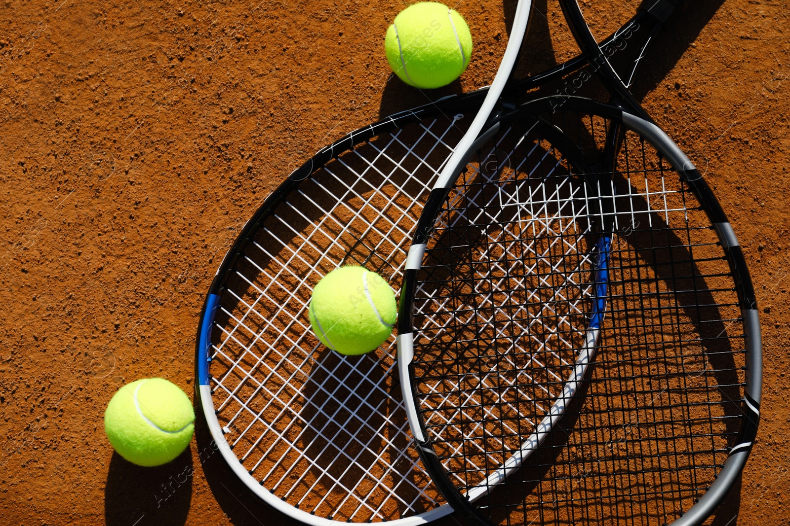 Photo of Tennis balls and rackets on clay court, flat lay