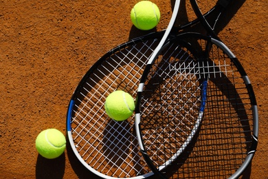 Tennis balls and rackets on clay court, flat lay