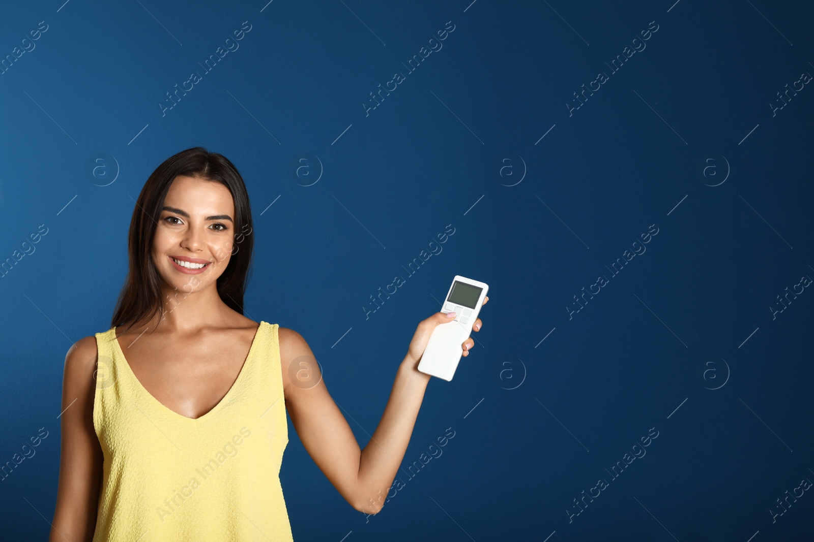 Photo of Young woman with air conditioner remote on blue background. Space for text