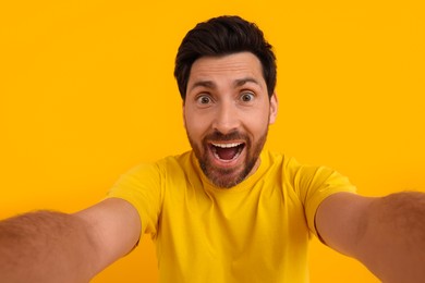 Photo of Happy man taking selfie on yellow background