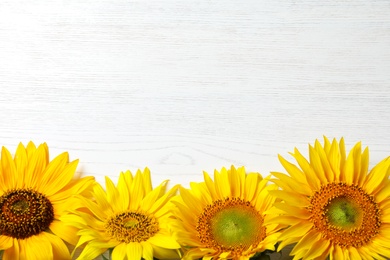 Photo of Yellow sunflowers on wooden background, top view