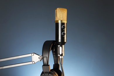 Photo of Stand with microphone and headphones on dark background. Sound recording and reinforcement