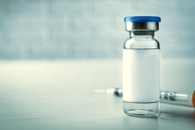 Image of Medication glass vial and syringe on white wooden table, space for text