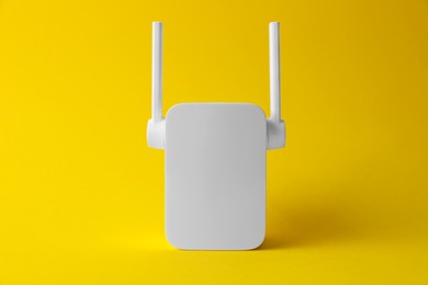 Photo of New modern Wi-Fi repeater on yellow background