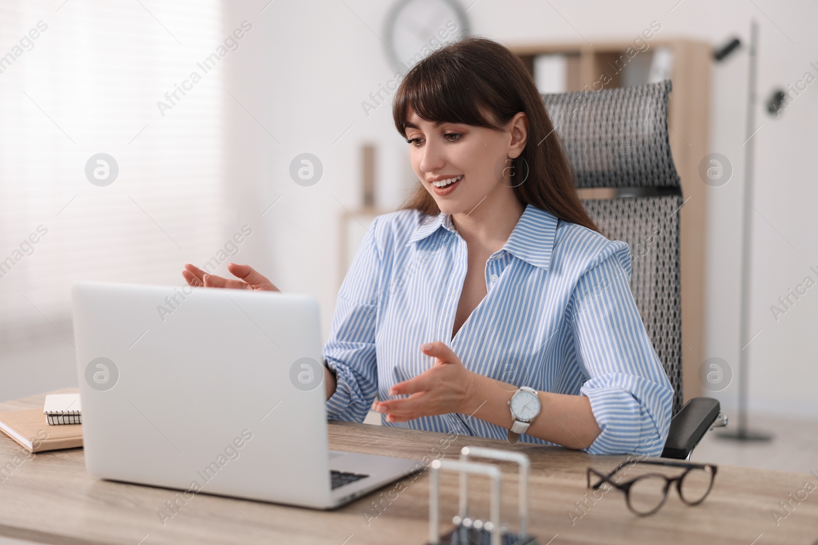 Photo of Woman using video chat during webinar at wooden table in office