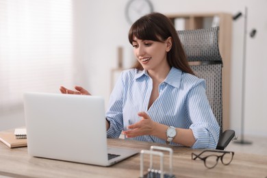 Woman using video chat during webinar at wooden table in office