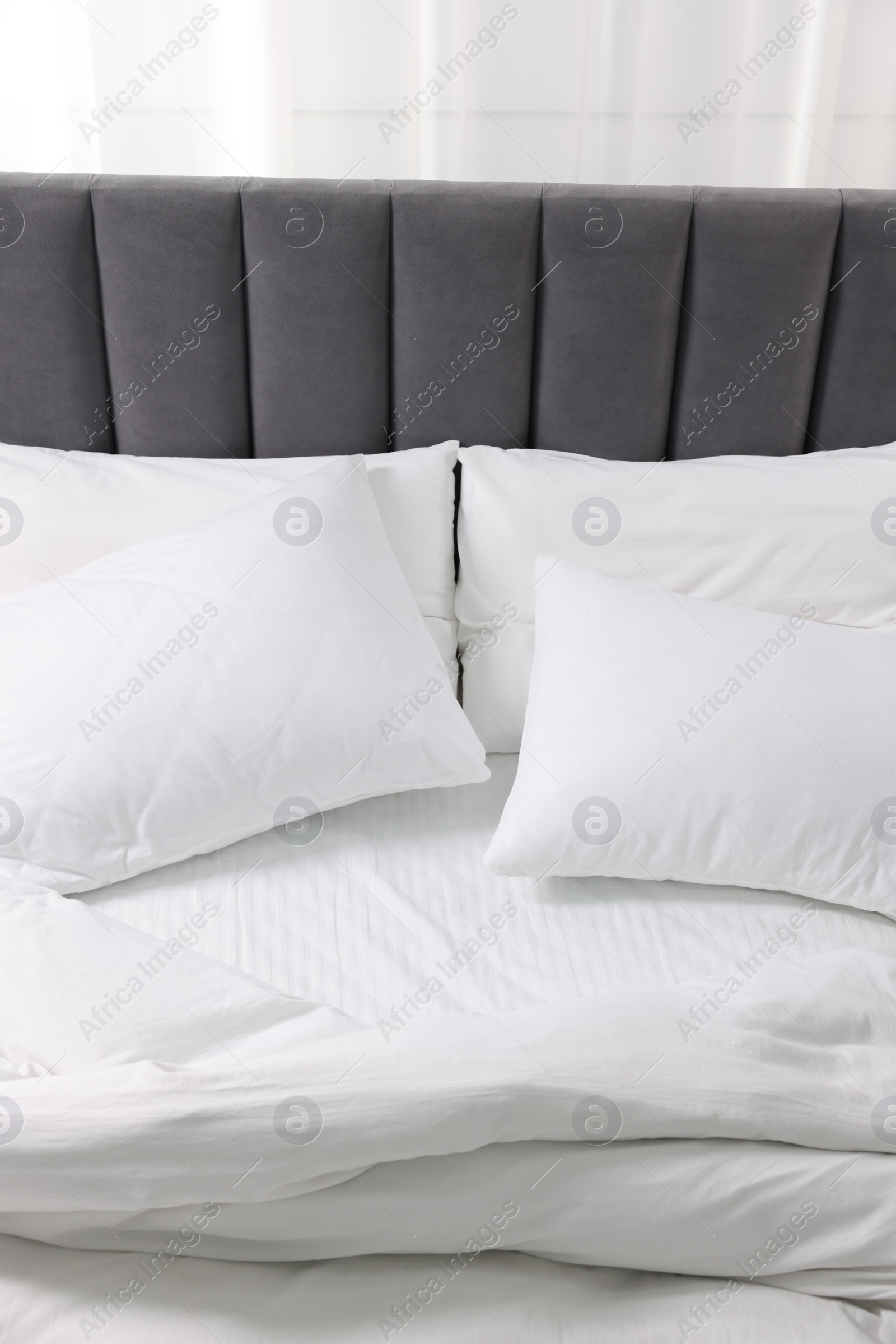 Photo of Soft white pillows and duvet on bed at home