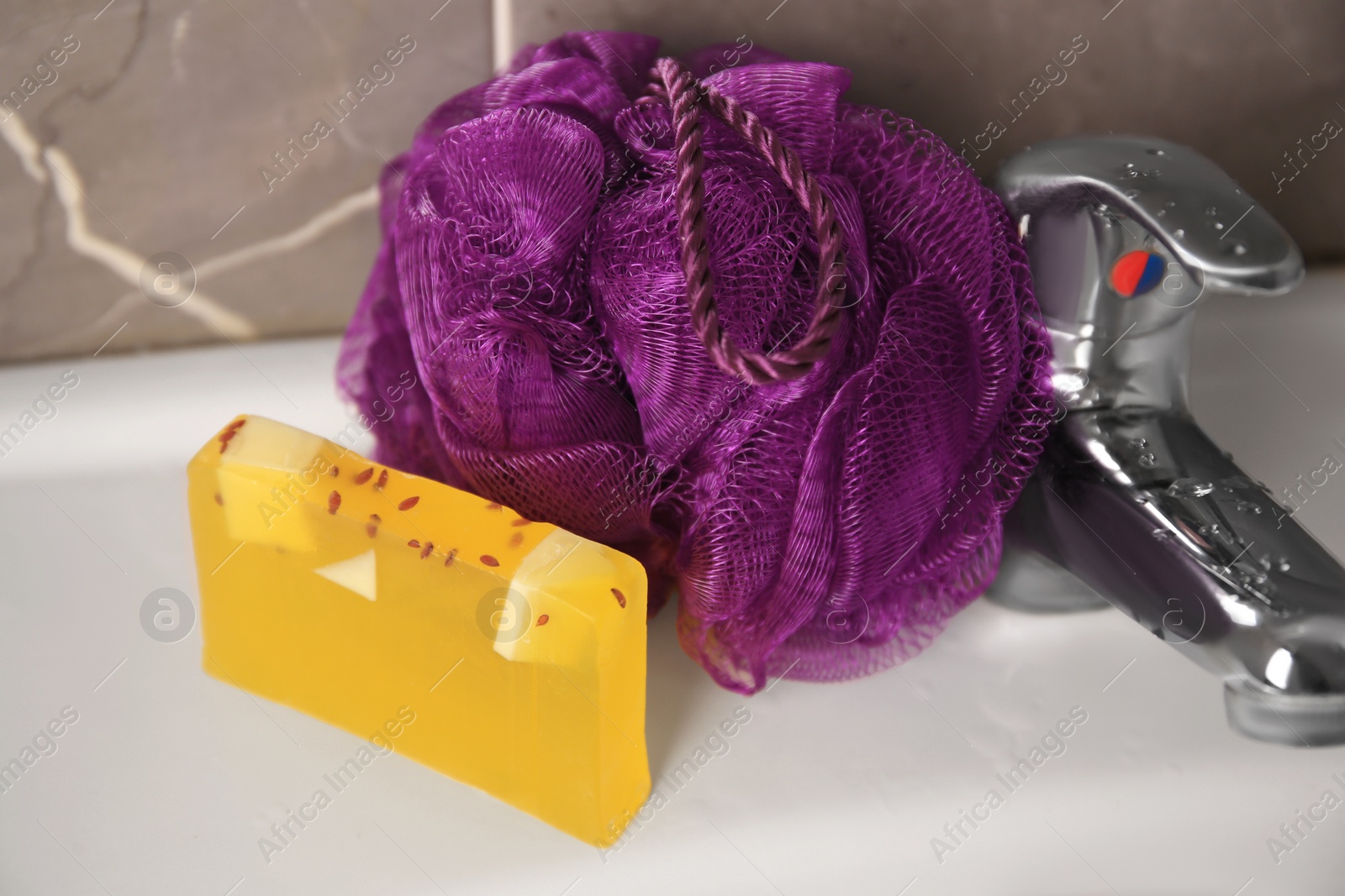 Photo of Purple shower puff and soap on sink in bathroom, closeup