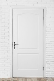 Photo of Closed white wooden door in brick wall