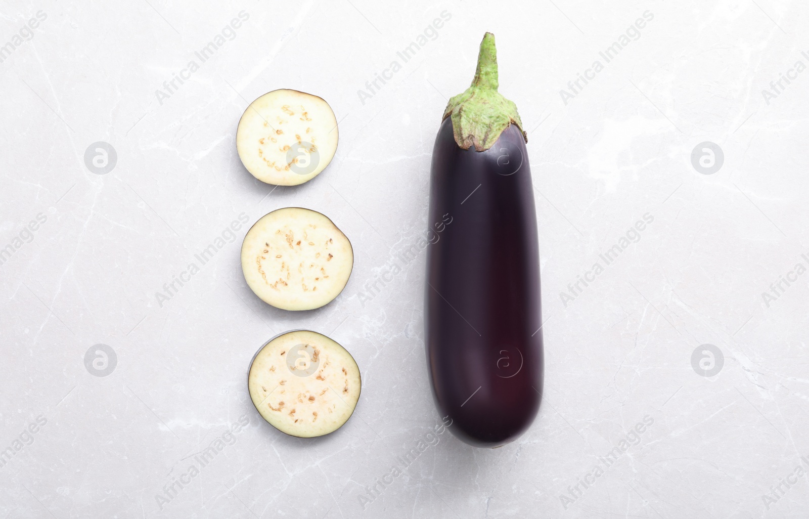 Photo of Cut and whole raw ripe eggplants on light table, flat lay