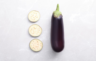 Photo of Cut and whole raw ripe eggplants on light table, flat lay