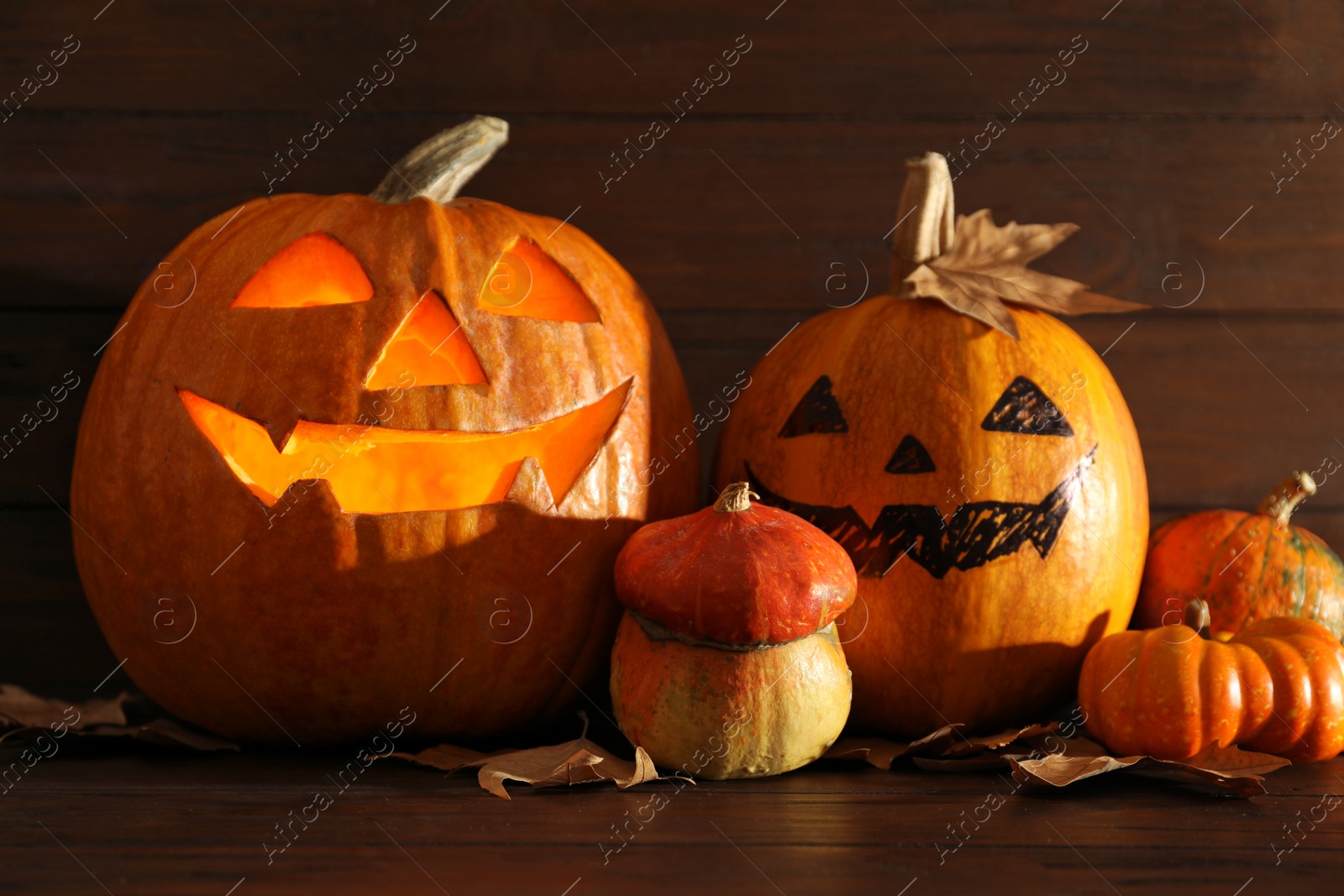 Photo of Halloween pumpkin head jack lanterns on table against wooden background