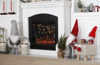 Photo of Cute Scandinavian gnomes and other Christmas decorations in room with near fireplace